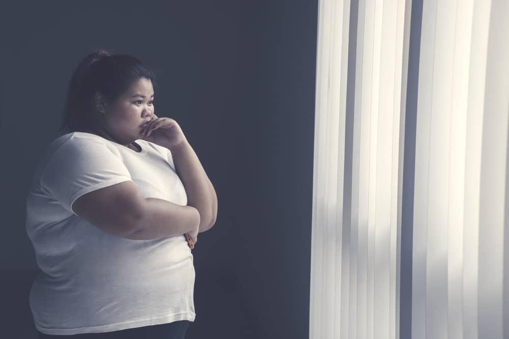 fat woman depressed looking out curtains