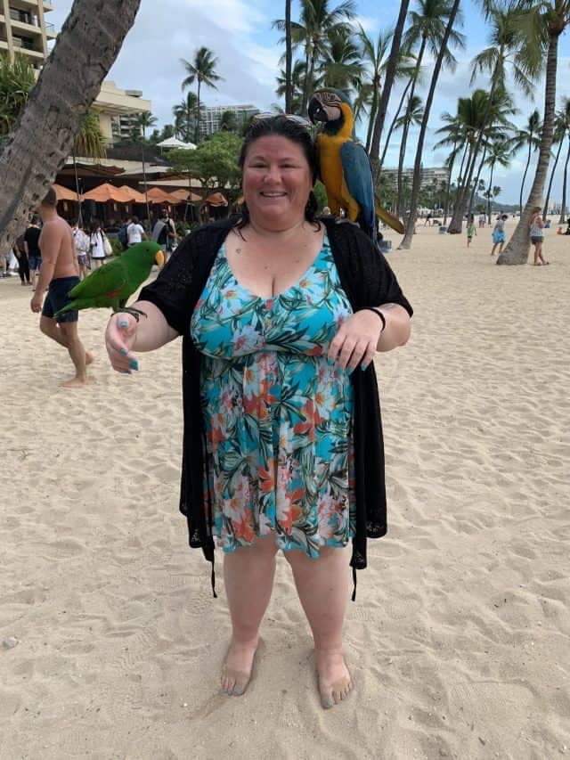 fat woman tish lee in a bathing suite on beach in Hawaii holding 2 birds 